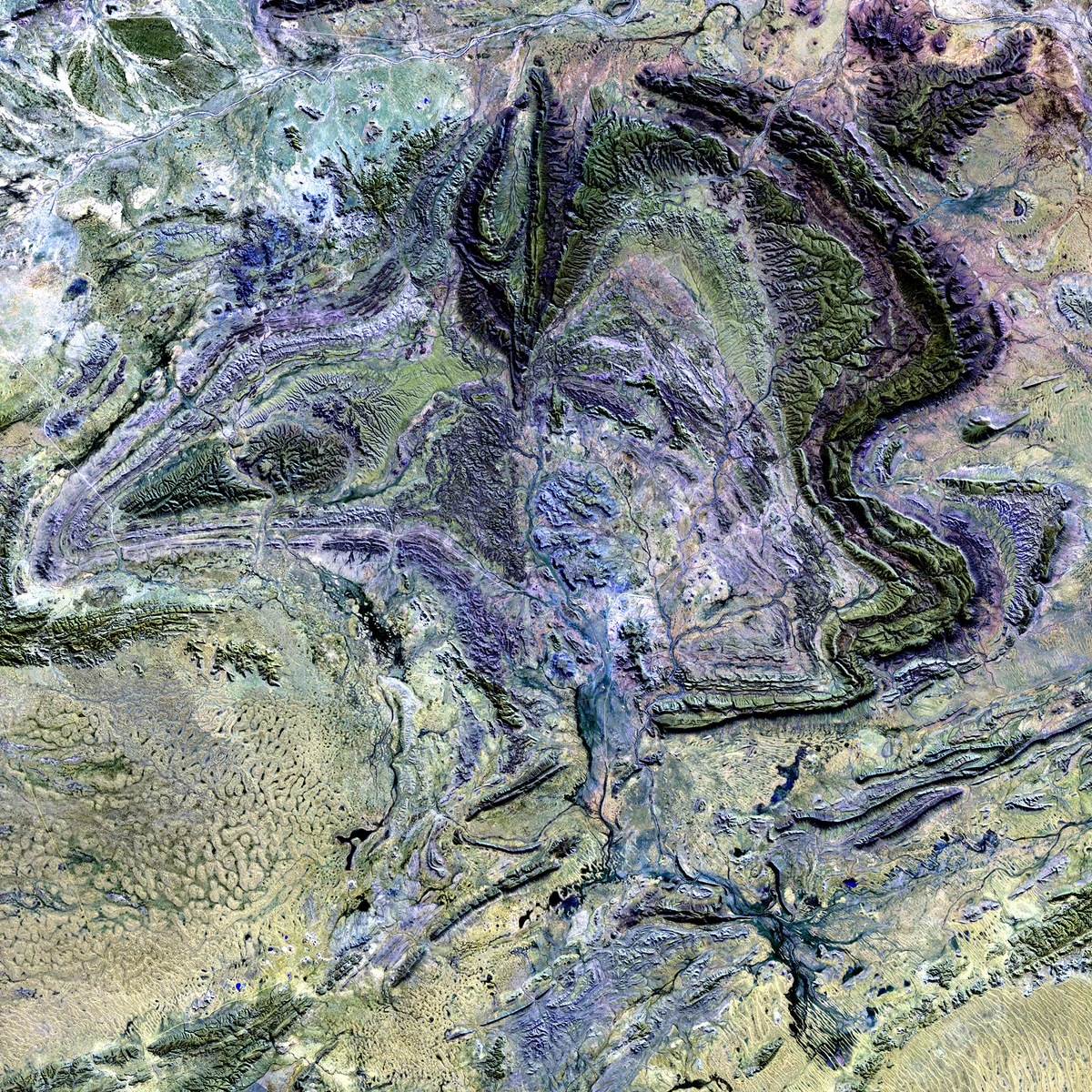 Folded ridgelines in grey, green and violet in a satellite image of the MacDonnell Ranges